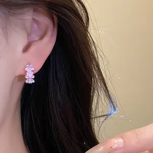 Close-up of sweet pink floral drip oil hoop earrings shown worn on the ear detail