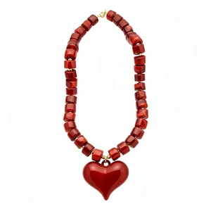 Collana di perle acriliche rosse con grande ciondolo a cuore lucido su sfondo bianco