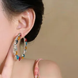 Detailed view of colorful zircon hoop earrings on model's ear, dopamine style jewelry