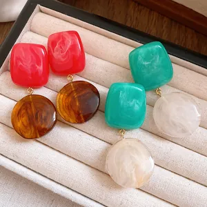 Gros plan de boucles d'oreilles en résine colorée avec texture marbrée dans un coffret