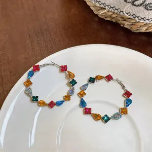 Detailed view of large colorful hoop earrings featuring square and teardrop zircon stones