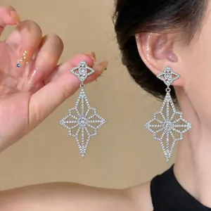 Detail showing silver star-shaped drop earrings with brilliant cubic zirconia inlays.