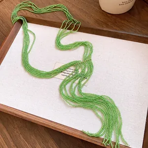 Detail of ethnic green crystal beaded multi-layer tassel necklace on a white display tray