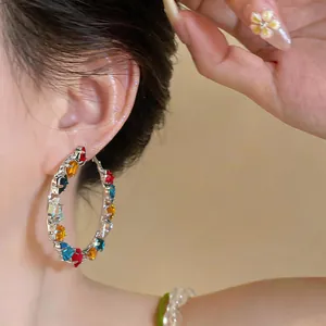 Detail view of vibrant colorful gemstone hoop earrings on model with dopamine style