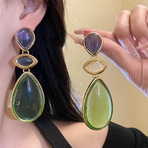 Close-up of vintage resin waterdrop dangle earrings with green and purple stones