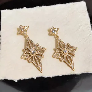 Detailed view of gold starburst earrings encrusted with sparkling crystals on texture.