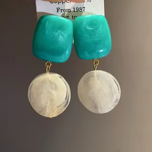 Gros plan de boucles d'oreilles pendantes en résine marbrée bleu sarcelle et blanc