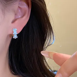 Detailed close-up showing light blue oil-drip flower earrings worn on a model ear