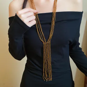 Detailed view of vintage ethnic multi-strand gold beaded tassel necklace on black top