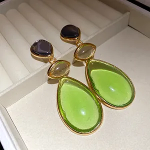 Close-up of vintage resin drop earrings with green and purple tiered pendants