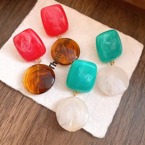 Vue détaillée de boucles d'oreilles en résine avec texture marbrée et contrastes