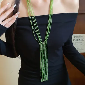 Detailed close-up of a multi-layer green beaded fringe necklace worn by a model