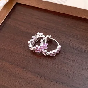 Detailed view of silver hoop earrings featuring delicate pink enamel flower patterns.