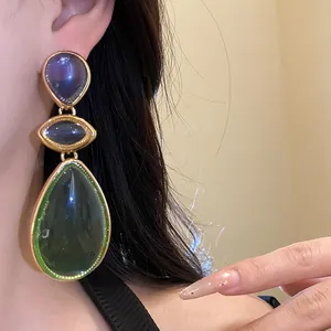Close-up of vintage-style resin drop earrings featuring multi-colored teardrop stones.