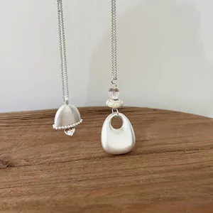 Detail view of a minimalist silver oval necklace with stone and glass beads