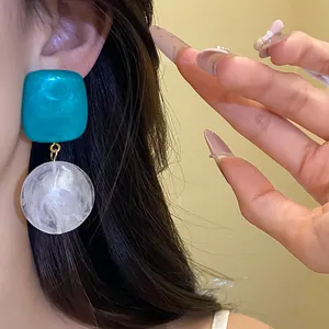 Gros plan de boucles d'oreilles pendantes rétro en résine bleue et blanche sur une femme