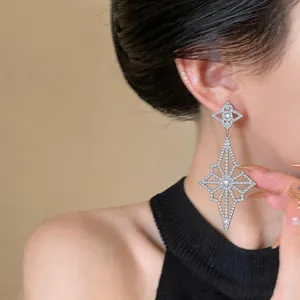 Close-up of elegant silver-tone rhinestone geometric star drop earring on model