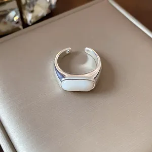 Primer plano de un anillo abierto geométrico plateado con una elegante resina blanca ovalada