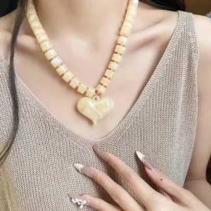 Dettaglio della collana di perle acriliche crema con grande ciondolo a forma di cuore