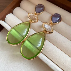 Close-up of vintage resin teardrop drop earrings in a gold-tone frame with lime green stones.