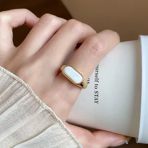 Detalle de anillo abierto chapado en oro de 18k con incrustación de resina blanca
