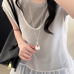 Detailed view of oval stone glass pendant necklace worn on minimalist layered outfit