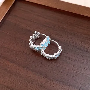 Close-up view of elegant light blue enamel floral hoop earrings with silver finish