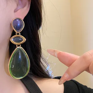 Close-up view of vintage green resin teardrop earrings with elegant gold-tone accents