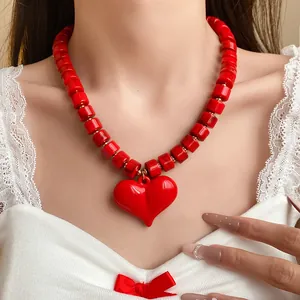 Dettaglio di una collana di perle acriliche rosse con un grande ciondolo a forma di cuore