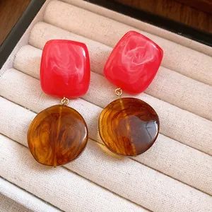 Gros plan de boucles d'oreilles rétro en résine avec carrés rouges et éléments ronds ambrés