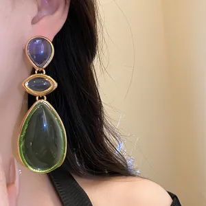 Close-up of vintage resin teardrop earrings in green and purple with gold setting.