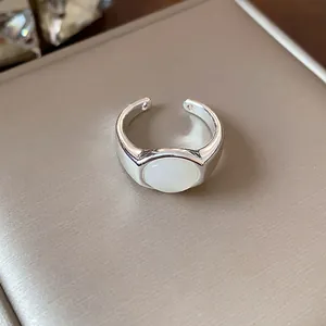 Primer plano de un anillo abierto plateado con una incrustación de resina blanca