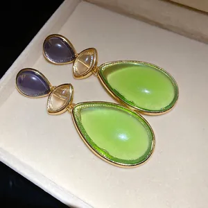 Detailed macro shot of vintage-inspired gold drop earrings featuring tiered green resin stones