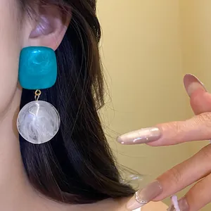 Gros plan détaillé de boucles d'oreilles pendantes en résine sarcelle et marbre chic