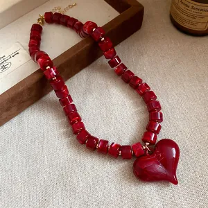 Primo piano della collana di perle acriliche rosse con dettaglio pendente a cuore lucido