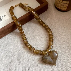Vista dettagliata di una collana di perle acriliche ambra con un grande ciondolo a cuore