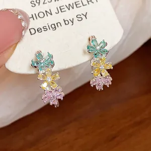 Detail of dainty zircon flower C-shaped earrings with colorful petals on a card
