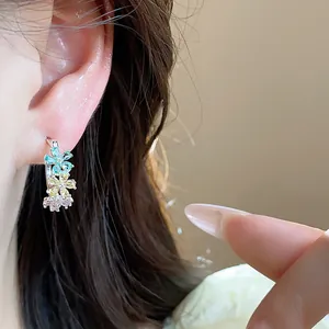 Macro detail of elegant C-shaped silver earrings featuring colorful zircon flowers.