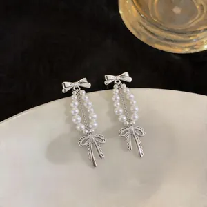 Dettaglio di orecchini a perla in stile francese con eleganti fiocchi argentati