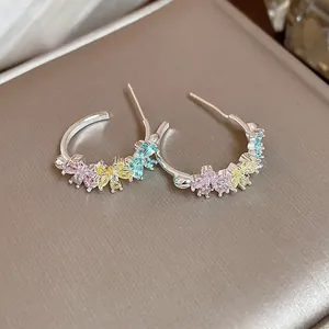 Detail shot of elegant C-shaped hoop earrings featuring colorful zircon flower accents