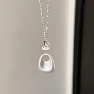 Macro view of minimalist oval pendant necklace with stone and glass beads detail