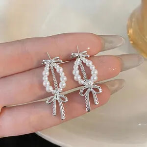 Vista dettagliata di eleganti orecchini a fiocco in argento con perle bianche lucide