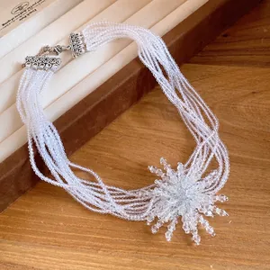 Collana multifilo in perline di cristallo con grande ciondolo a forma di fiore.