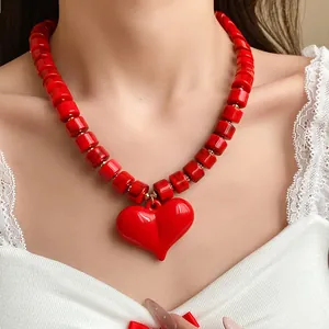 Primo piano di una vivace collana di perline in acrilico rosso con un grande ciondolo a cuore 3D.
