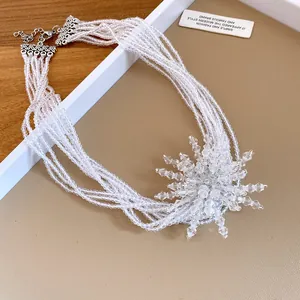 Primo piano di una collana multistrato in perle di cristallo con pendente a forma di stella.