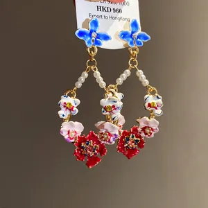 Detailed macro view of colorful enamel floral earrings with pearls and crystals.