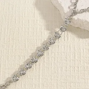 Detailed view of a silver heart-shaped rhinestone body chain on a textured background