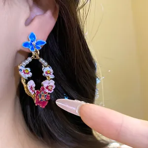 Close-up detail of vintage-style floral earrings featuring pearls and colorful enamel flowers