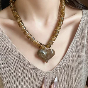 Primo piano dettagliato di una collana con pendente a cuore in acrilico e perle ambrate