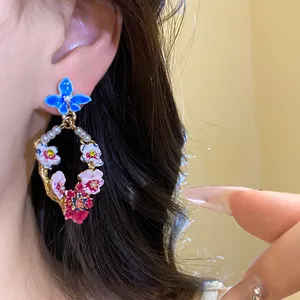 Macro detail of vintage floral enamel wreath earring with pearls and colorful rhinestones.